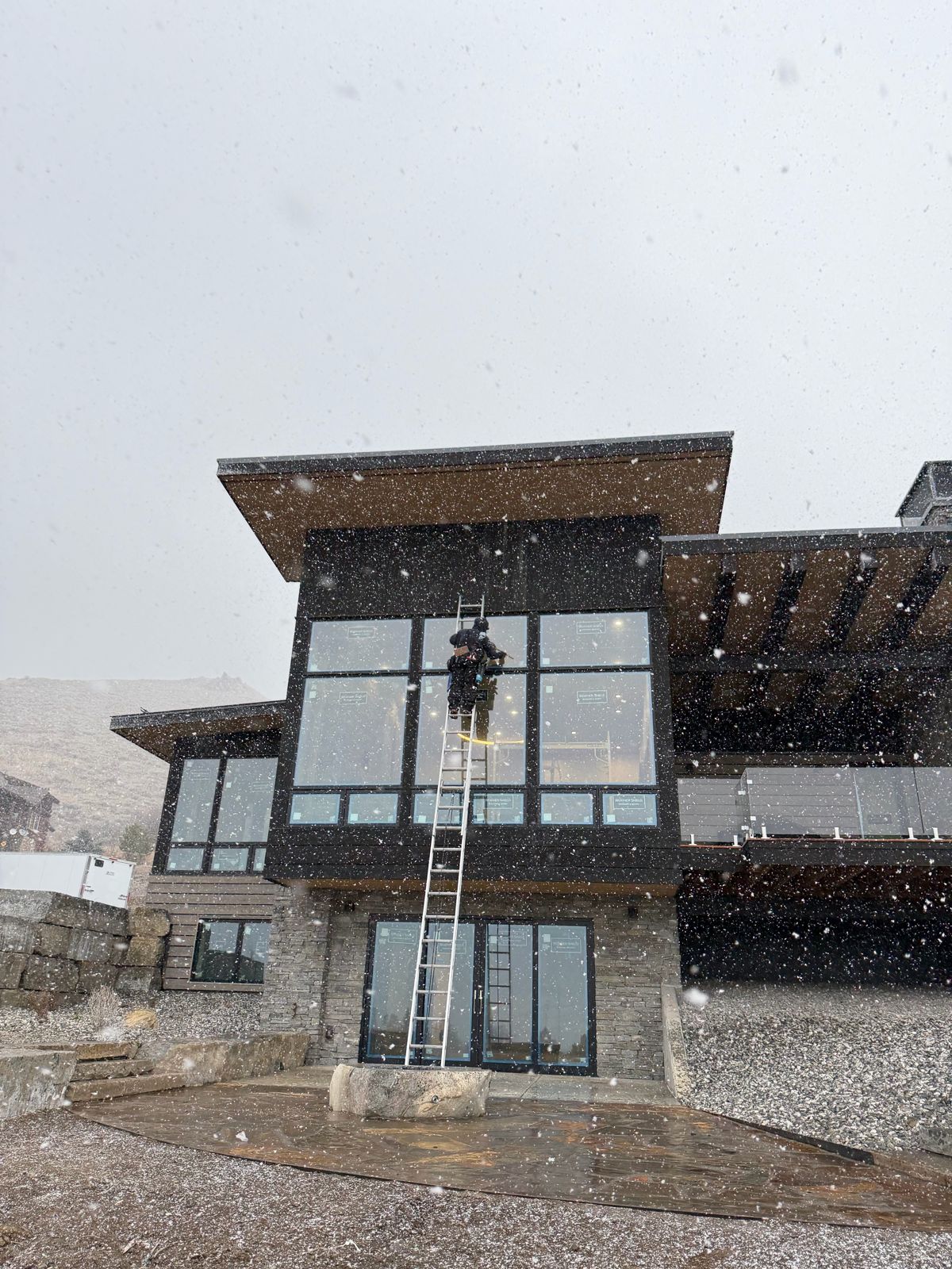 Window cleaner on a ladder at a modern home in the snow