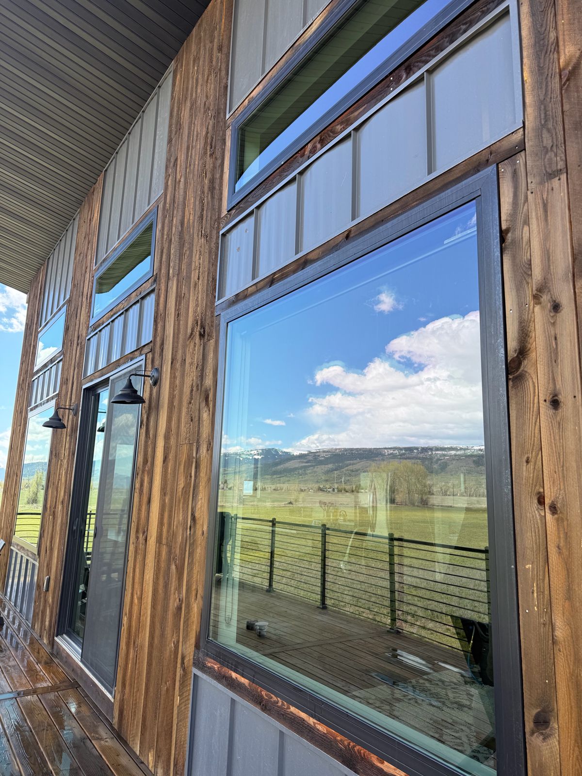 Clean picture window reflecting the valley and mountains on a wood-sided Driggs home