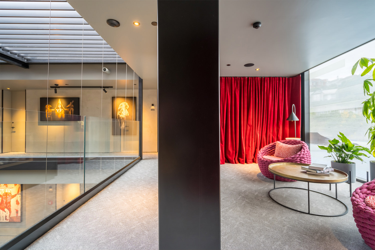 A photo of the inside of the Ebb Hotel with a bright red floor to ceiling curtain and lots of artwork on the corridor walls