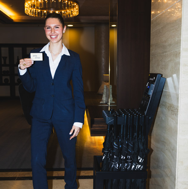 Hotel receptionist next to a Dripdrop umbrella stand in the lobby