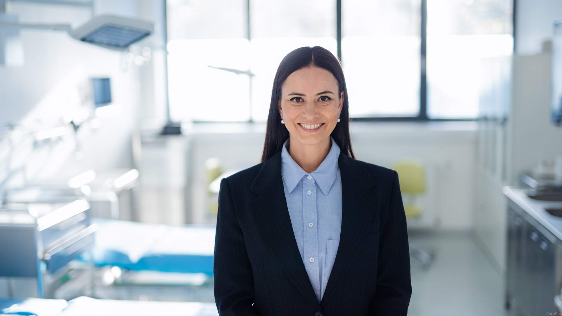 A woman who is a clinical director stands in a blue blazer in a medical facility.