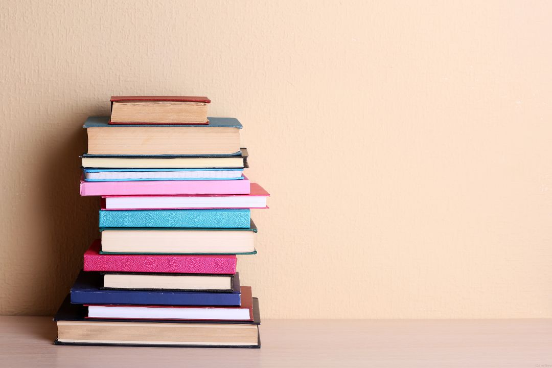 A stack of Physical Therapy books sits on a table.