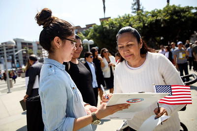 a woman helping another woman register to vote, one women is holding a clipboard the other is holding a small American flag