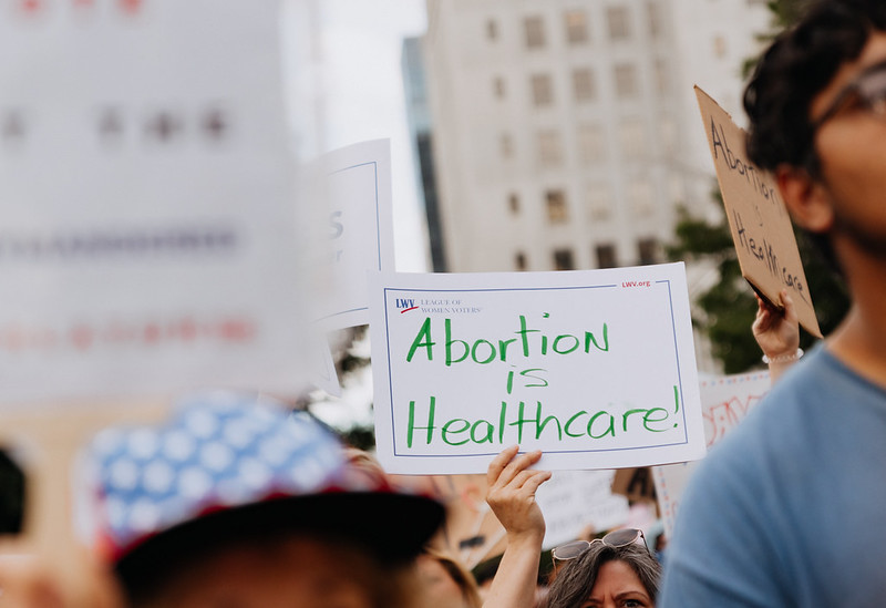 a hand holding a sign at a rally that says "Abortion is healthcare!"