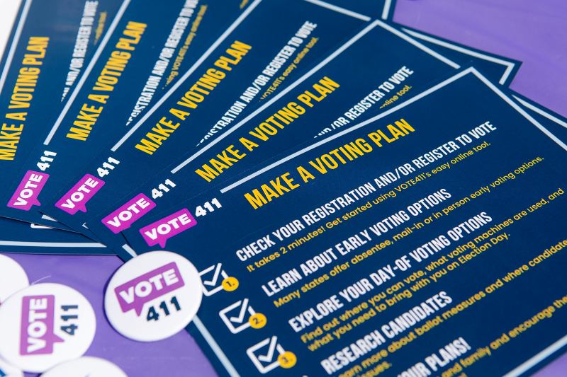 a stack of Vote411 postcards fanned out in a display with Vote411 buttons on top