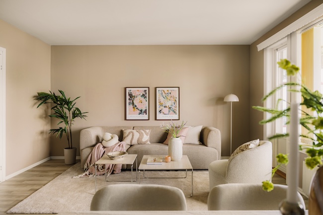 Stue med sofa, bord og lenestol sett fra spisegruppen innredet med beige og rosa toner, feminint formspråk på møbler