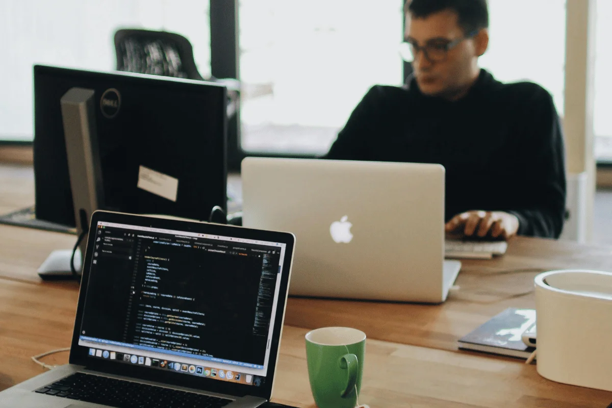 Two software developers working on their laptops in a modern office environment.