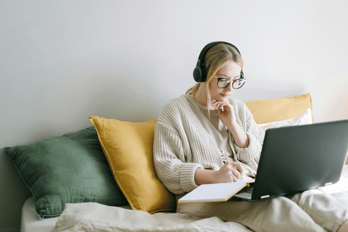 Concentrated female with headphones working on a laptop in a relaxed home environment.