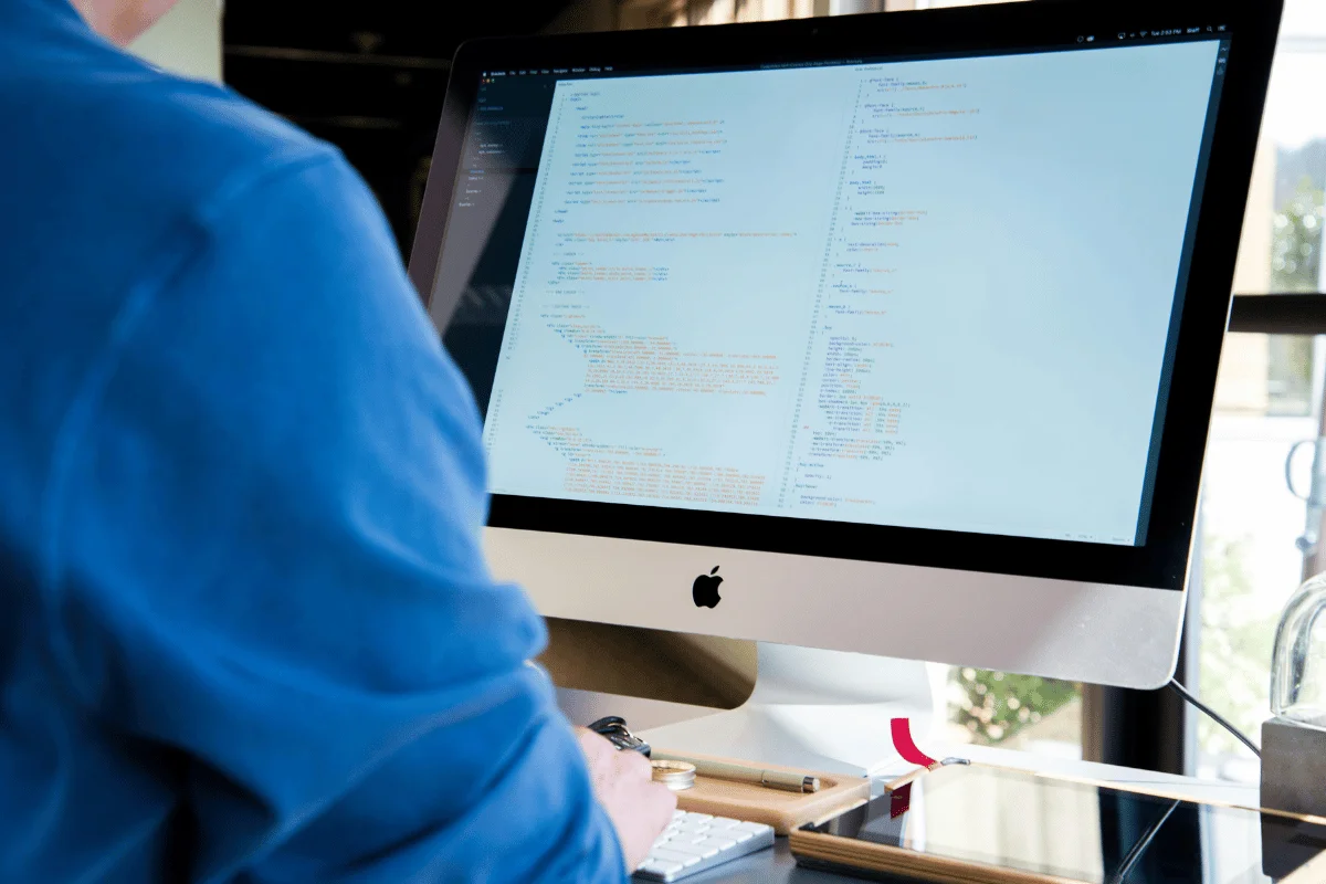 Software developer working on a coding project, typing on a sleek iMac computer.