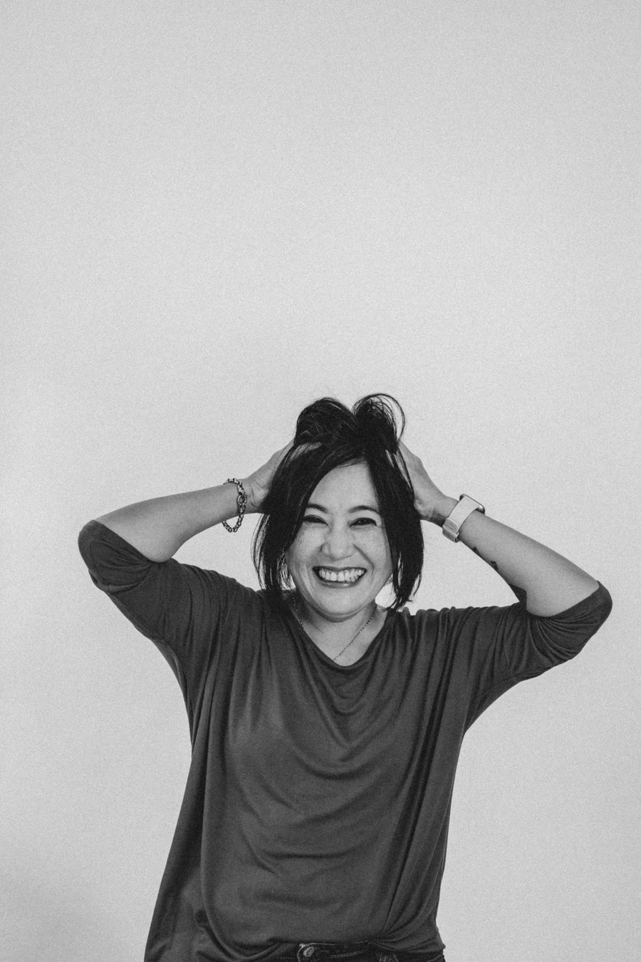 Novi from Blast Away Guys smiling with her hands on her head in a playful portrait.