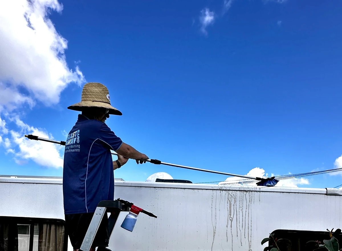 Blast Away Guys technician using a soft brush on an extendable pole to wash the exterior of a motorhome.