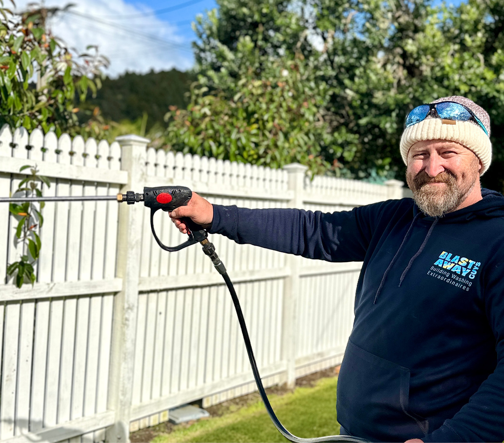 Josh washing a tall white picket fence in Russell BOI