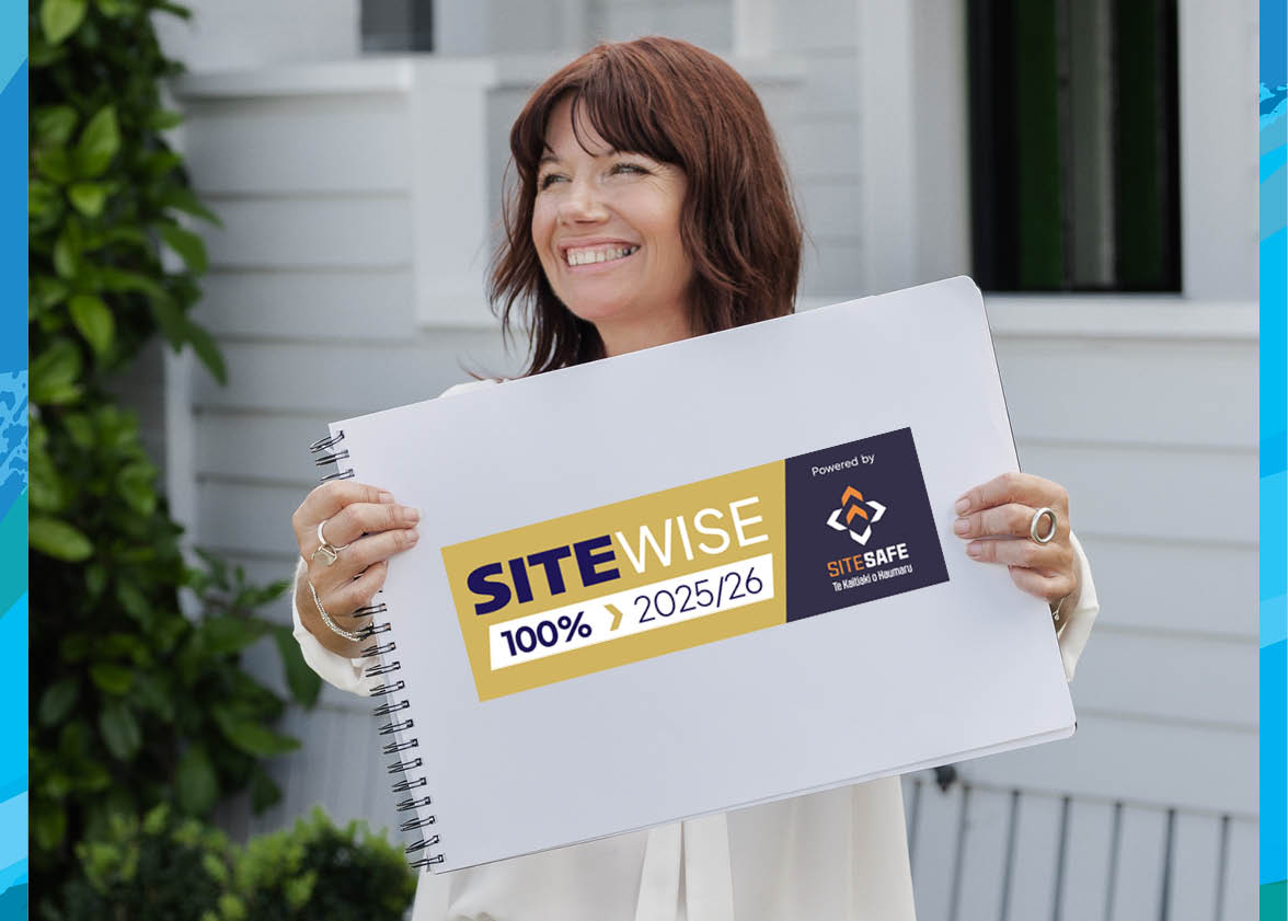 Brya from Blast Away Guys smiling and looking to the side while holding a notepad showing the company’s 100% SiteWise Gold accreditation in New Zealand