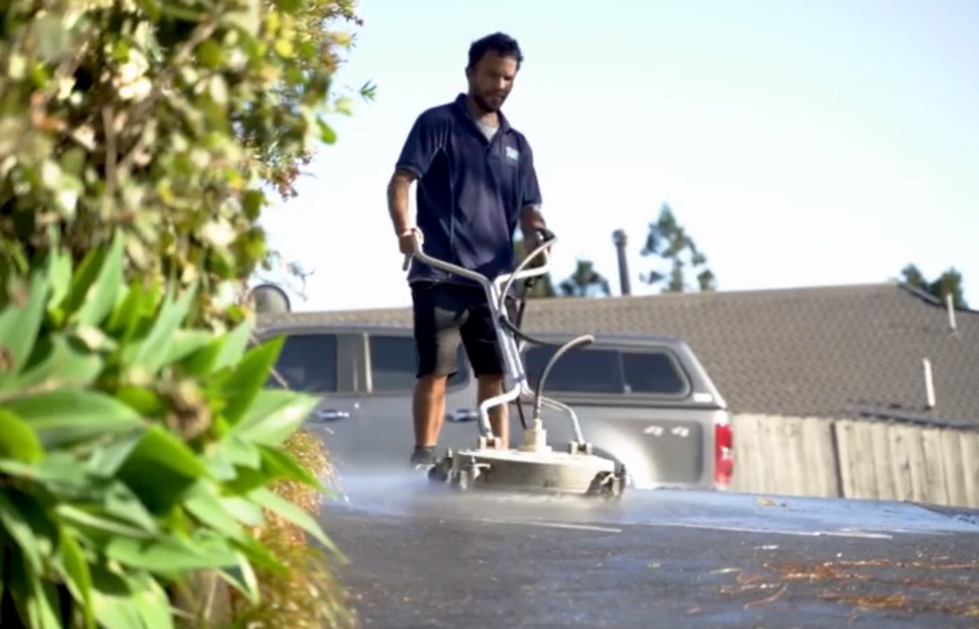 Blast Away Guys technician using a surface cleaner attachment on a concrete driveway in Northland.