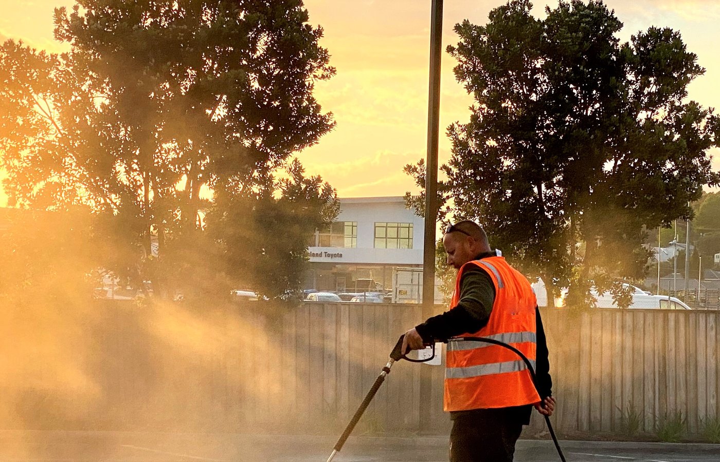 Blast Away Guys technician hot water blasting a commercial carpark at golden hour.