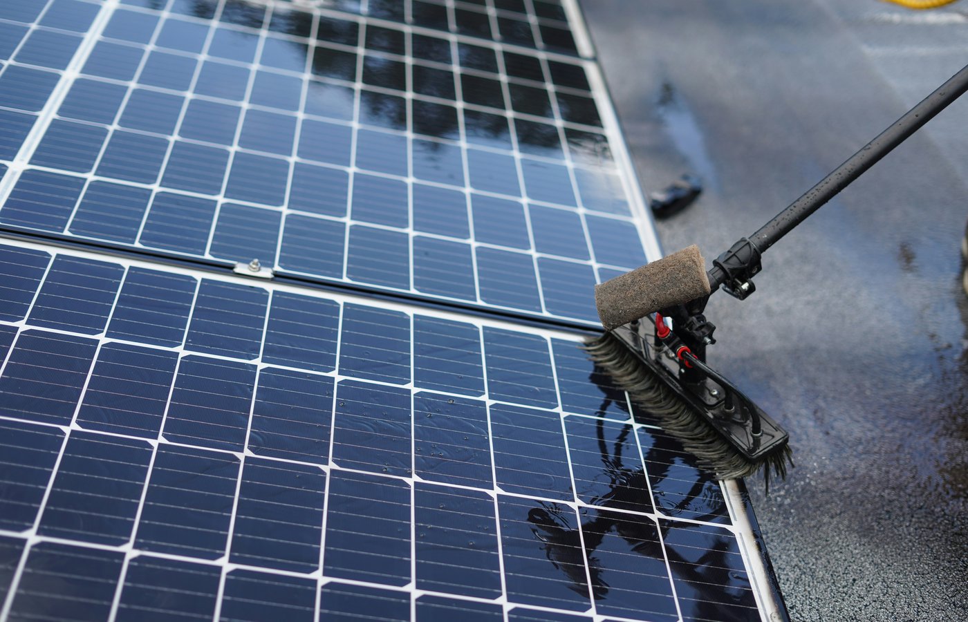 Close-up of a soft brush cleaning a solar panel using a water-fed pole system.