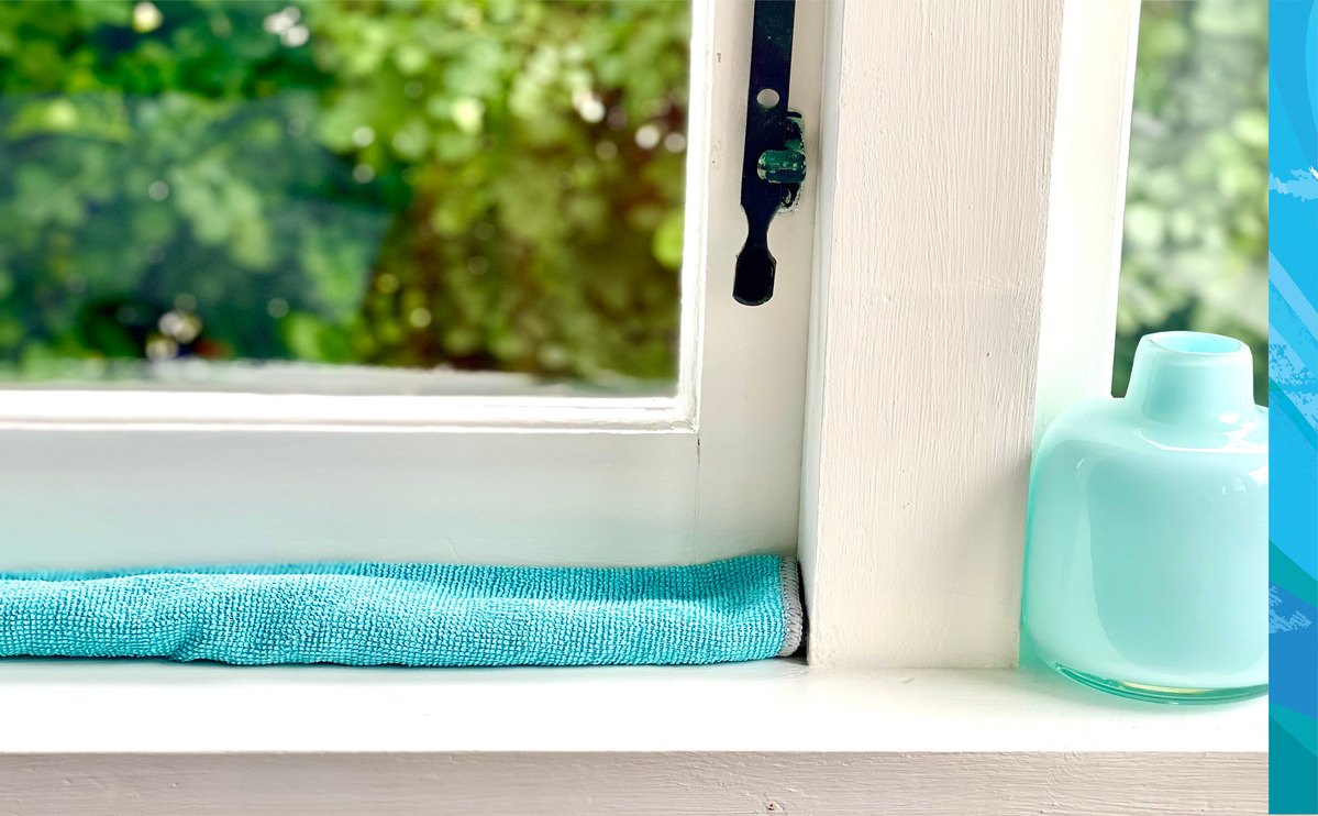 An old towel along the inside sill of a wooden window before exterior washing