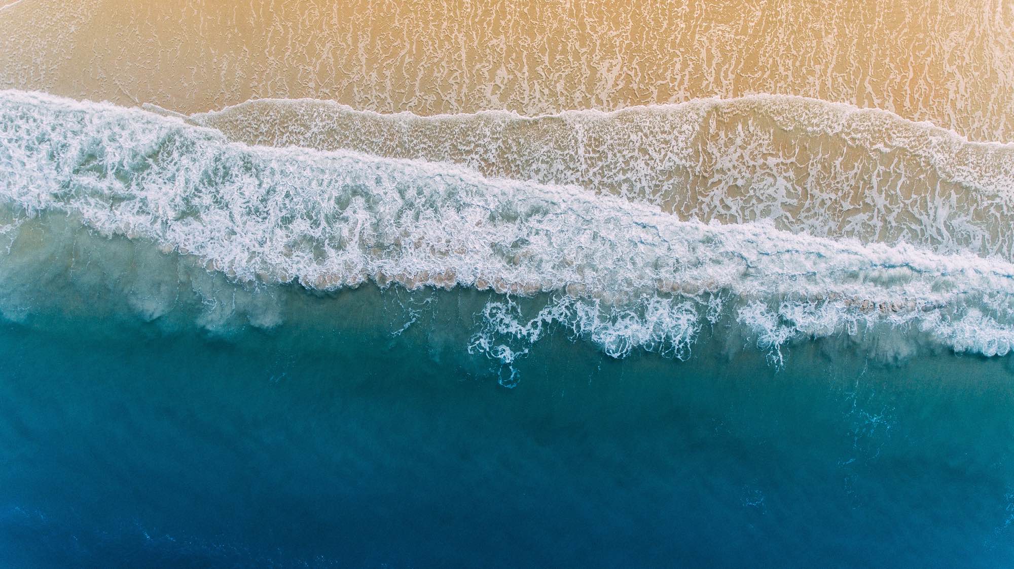 Ocean waves crashing on a beach, birds-eye-view