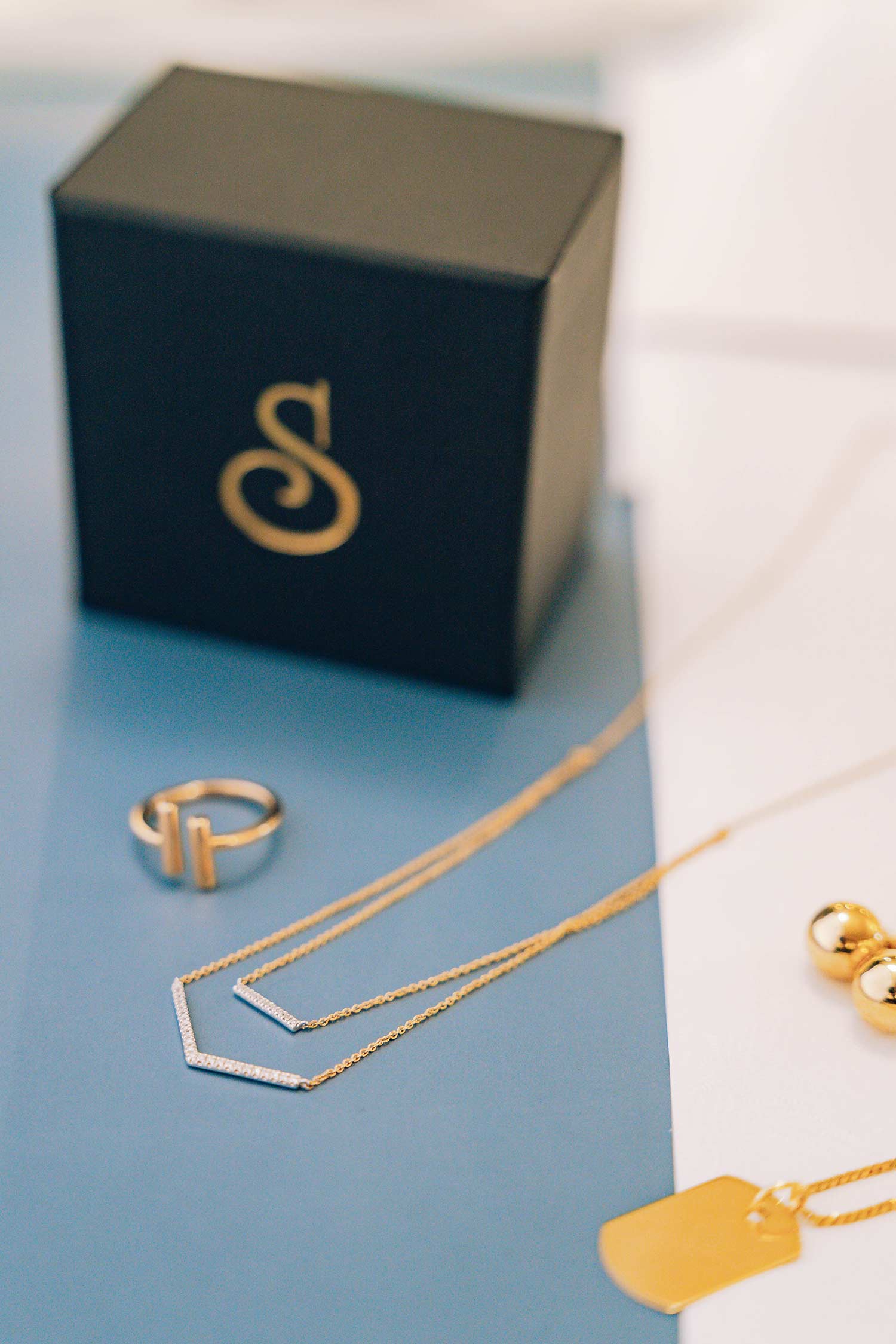 a few gold jewellery pieces beside a Swanson's Jewellers jewellery box