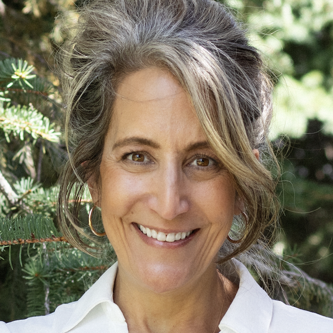 Woman in front of evergreen smiling