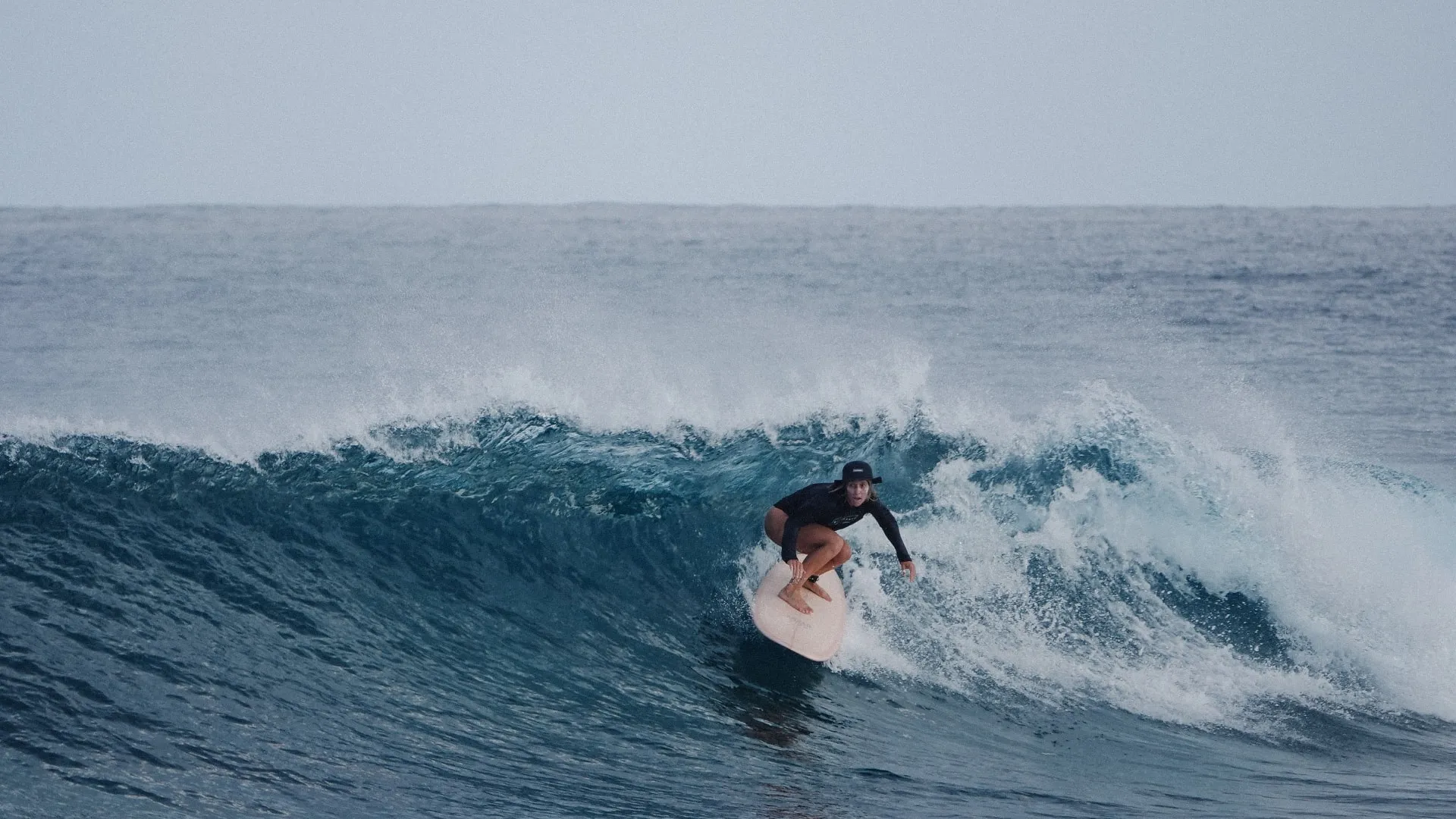 surfer girl racing backside down the line, in the maldives
