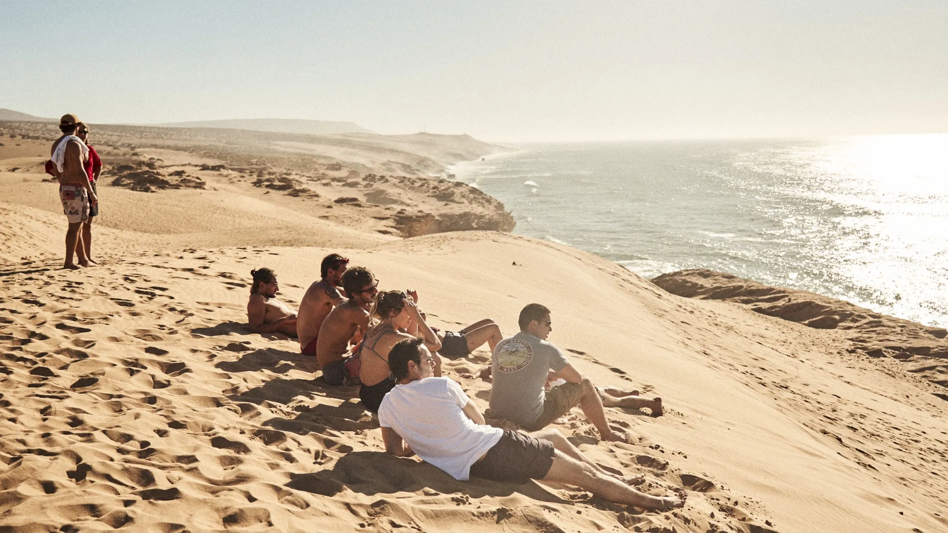 Friends relaxing on the dunes together in front of the sea