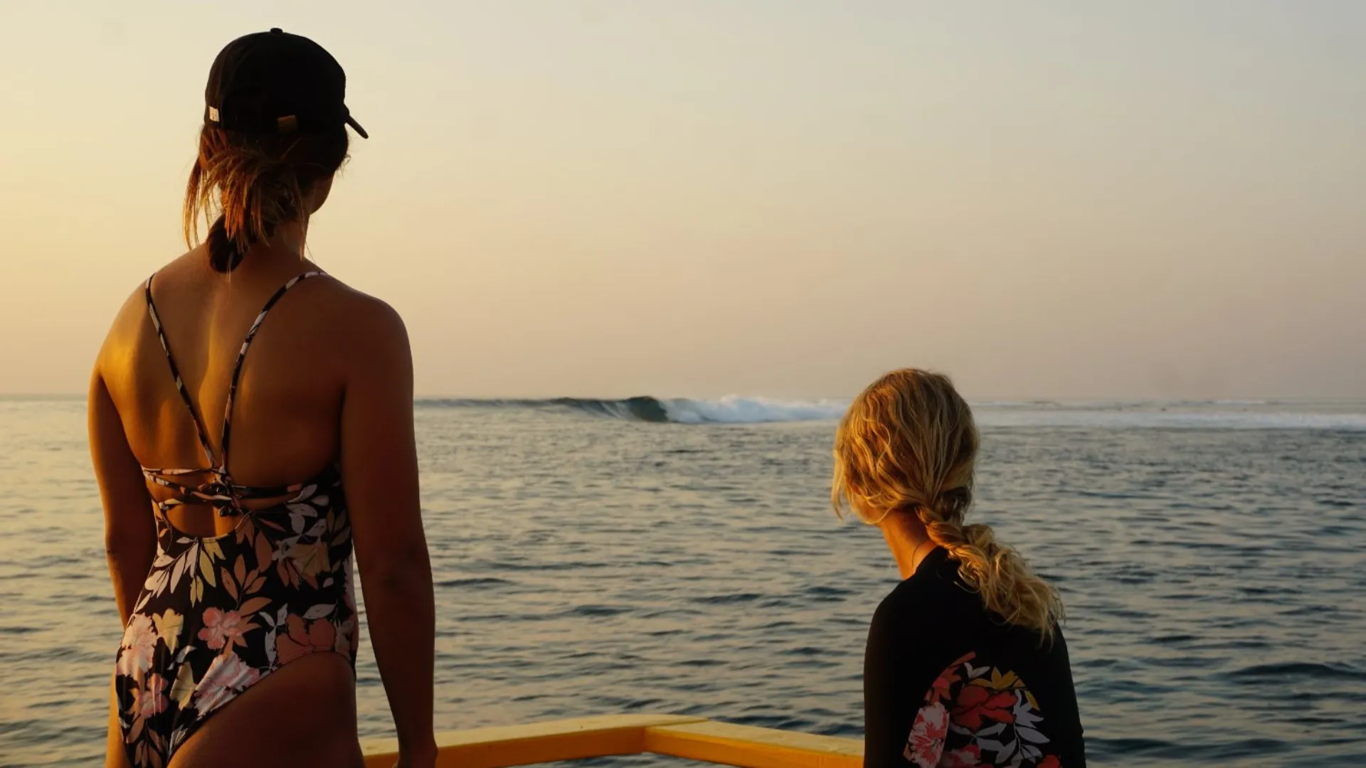 two girls looking at the waves from the dinghy boat. Ready to jump in the lineup at sunset in the Maldives
