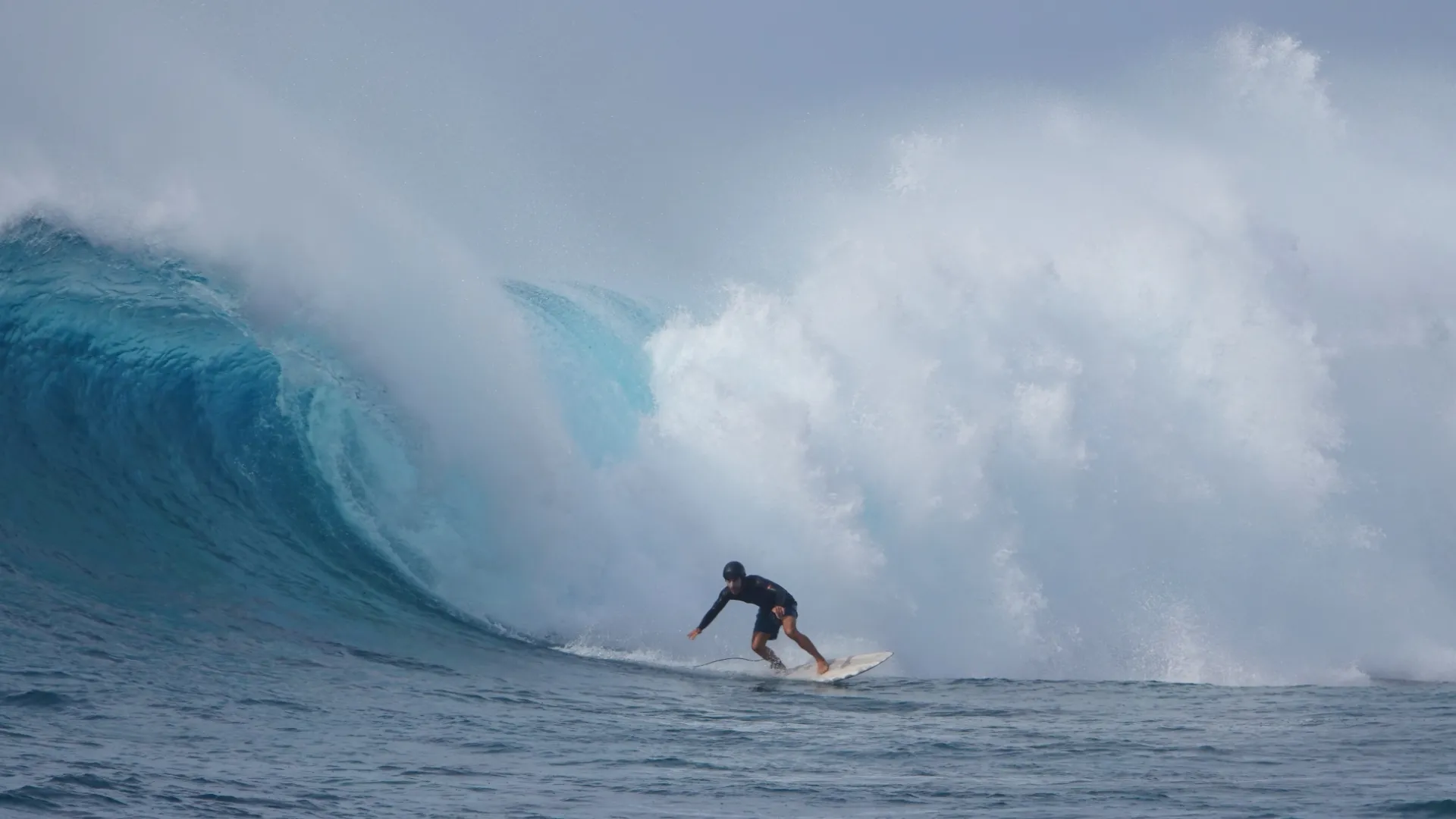 Surfer drops on an overhead barreling wave in the Maldives