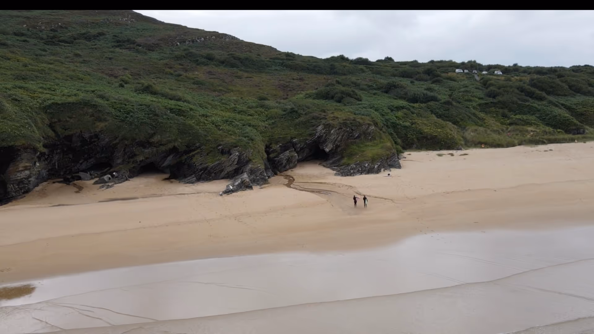 surfers walking on the beach in ireland