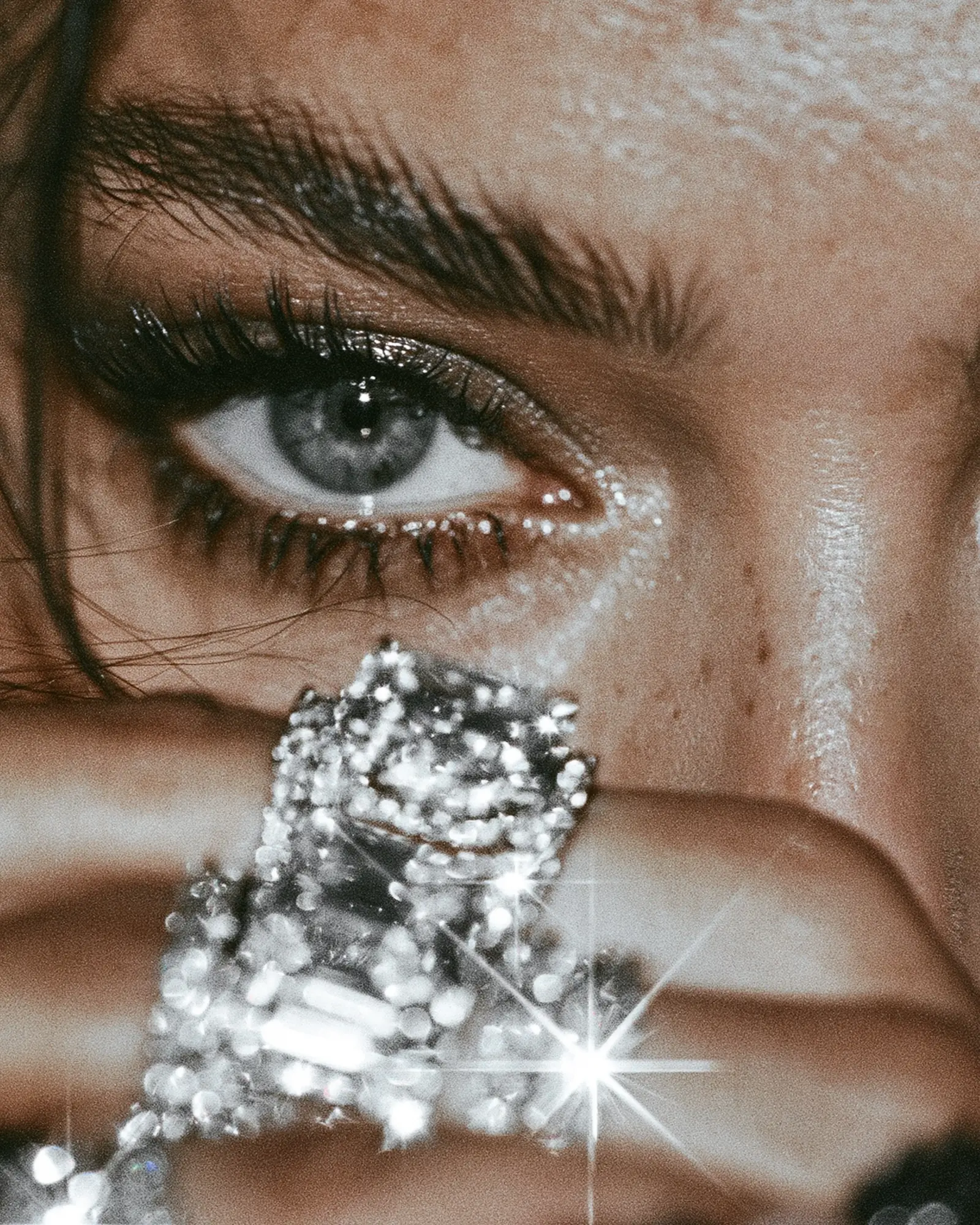 Close-up of an eye above a hand wearing a diamond ring