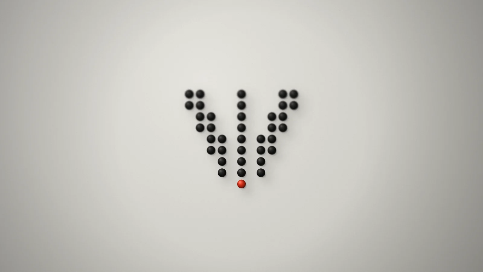 The Volante dot-V laid out in small matte black spheres on a pale grey backdrop, ending in a single orange-red sphere