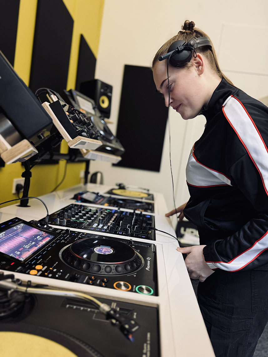 A DJ lesson gift experience in action. A young woman learns how to DJ.