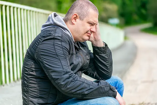 Man sitting outdoors looking distressed, illustrating the emotional impact of OAB