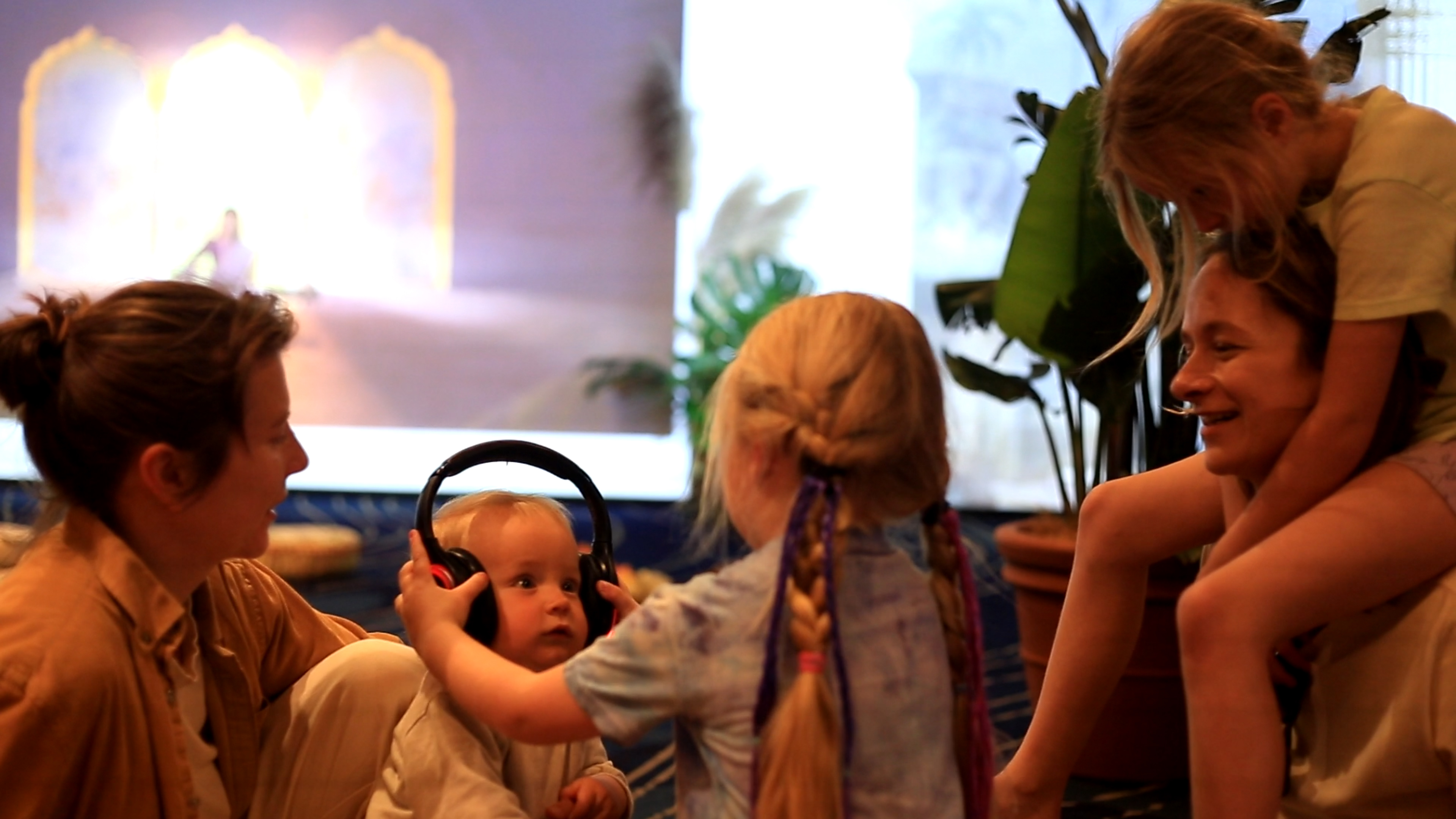 A toddler trying on silent-disco headphones, surrounded by smiling family