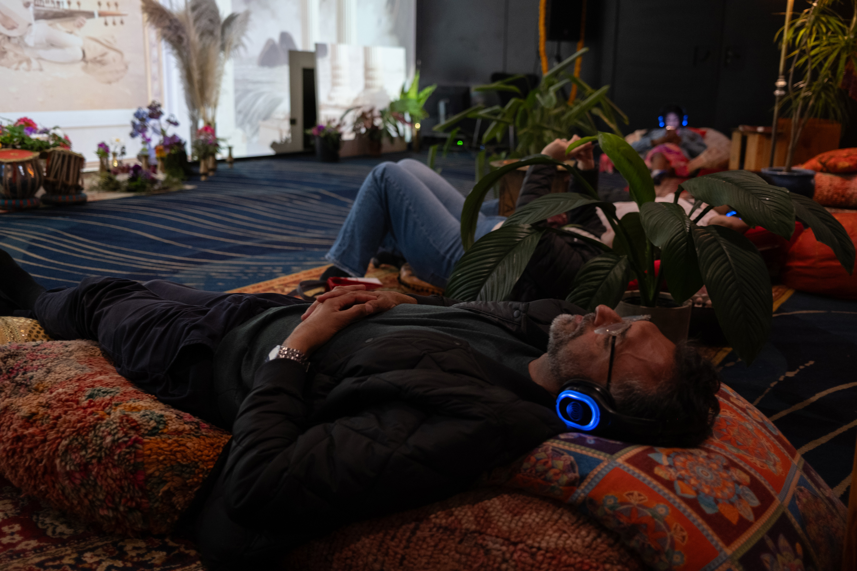 A guest relaxing on floor cushions with glowing silent-disco headphones