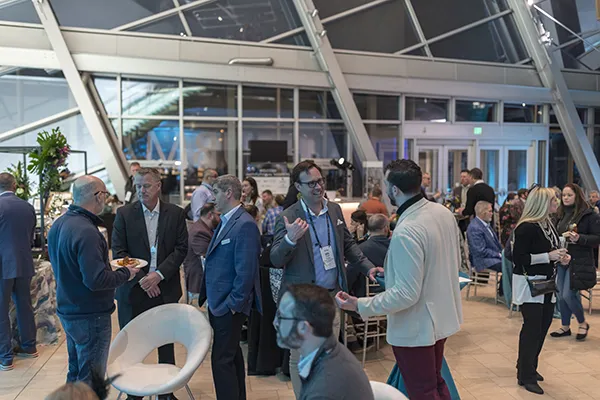 Group of people networking and chatting at By Design networking event.