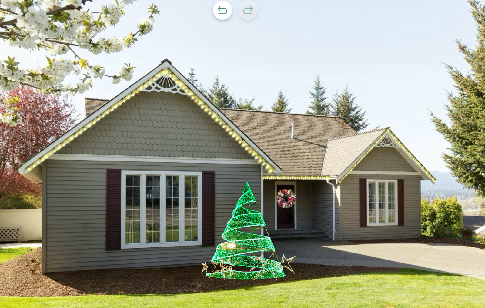 Front view of a suburban home decorated for the holidays with warm white roofline lights, a festive wreath on the door, and a glowing green spiral Christmas tree structure in the front yard.