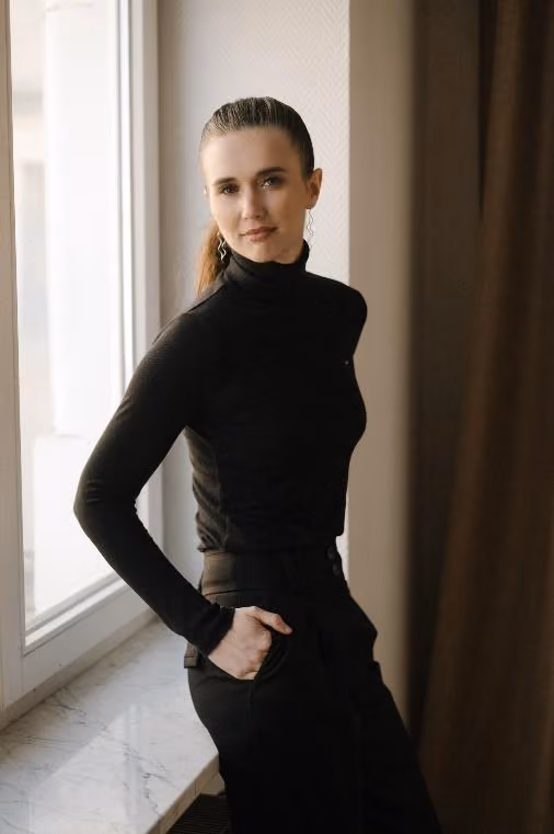 A person in black standing in front of a windowAI-generated content may be incorrect.