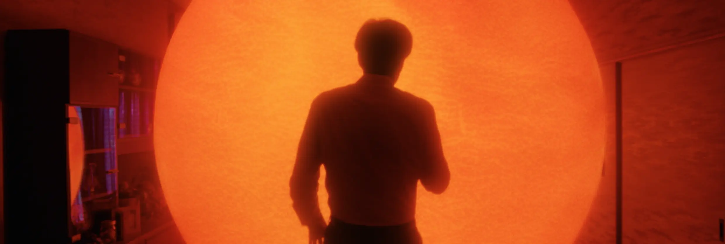 A person standing in front of a glowing sun-like sphere with the text Filmsupply overlaid