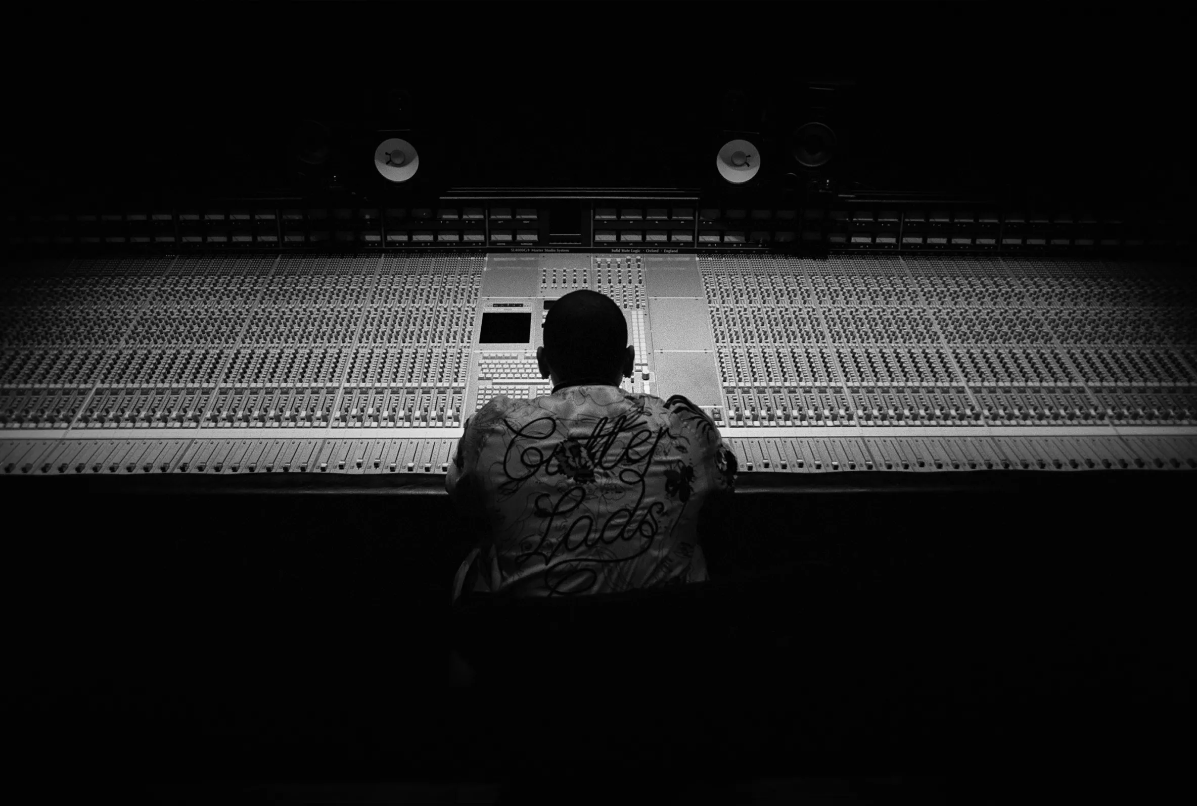 A person sitting at a large audio mixing console