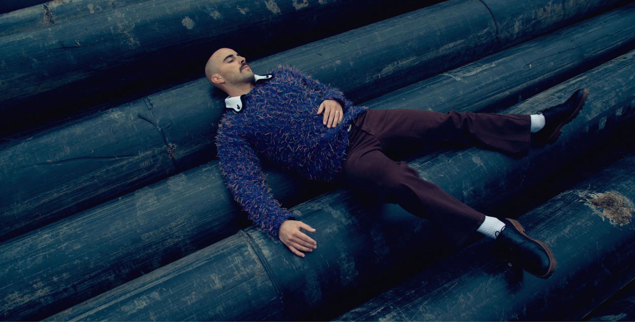 A man laying down on group of large wooden beams