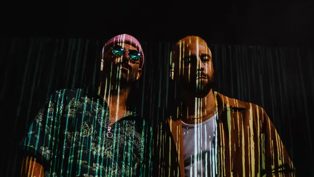 Motorcycle riding on a dirt road winding through a rocky desert canyon landscape.