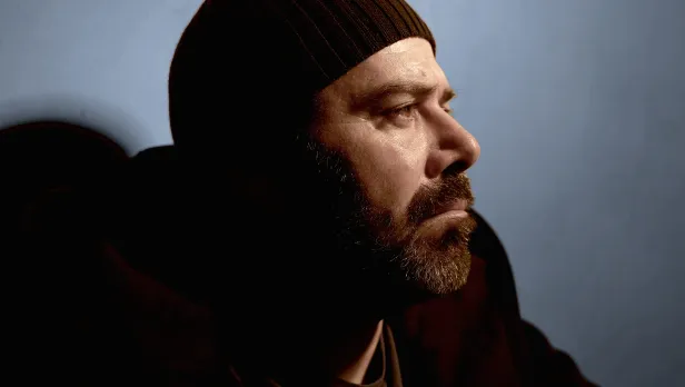 Motorcycle riding on a dirt road winding through a rocky desert canyon landscape.