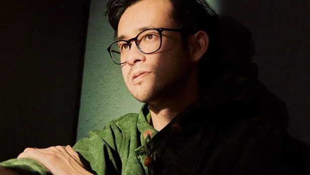 Motorcycle riding on a dirt road winding through a rocky desert canyon landscape.