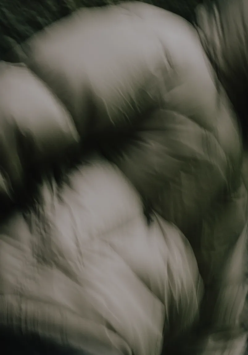 Close-up of dark green puffer jacket fabric with visible stitching and quilted sections.