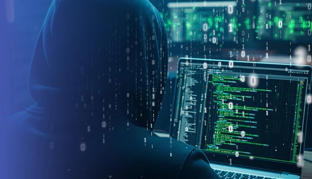 Screen with source code, next to it an unrecognizable person with a hood and hidden face tapping on the screen.