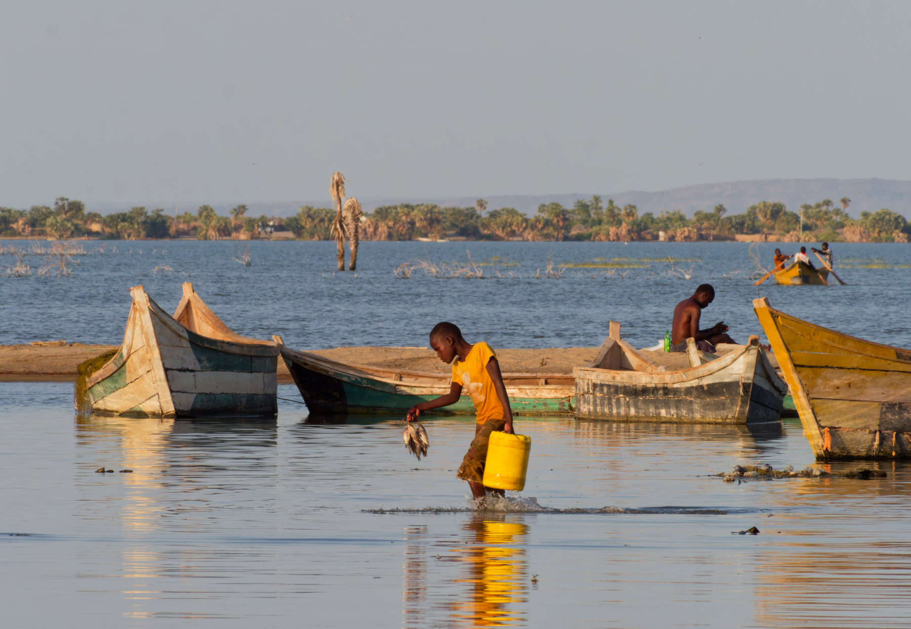 Girl wading through Lake Turkana with jerry can of water.