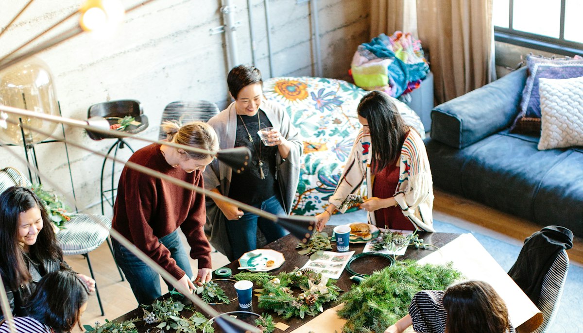 People gathered around a long table making seasonal wreaths at a creative small-business workshop