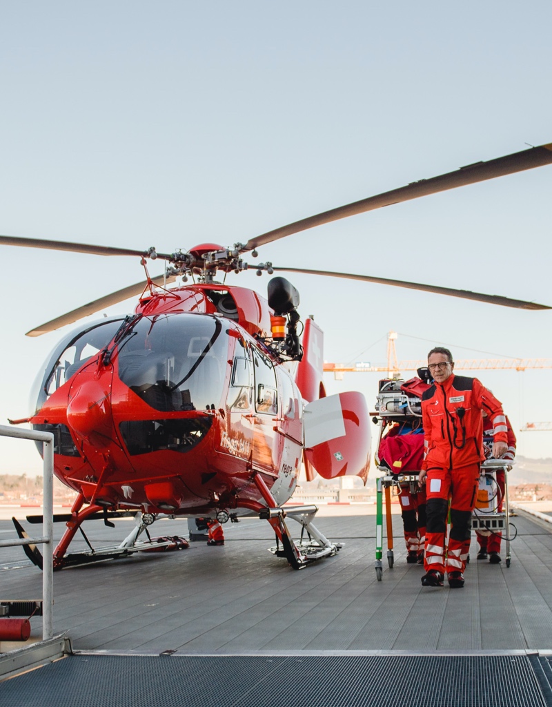 Rega helicopter next to a paramedic and a stretcher