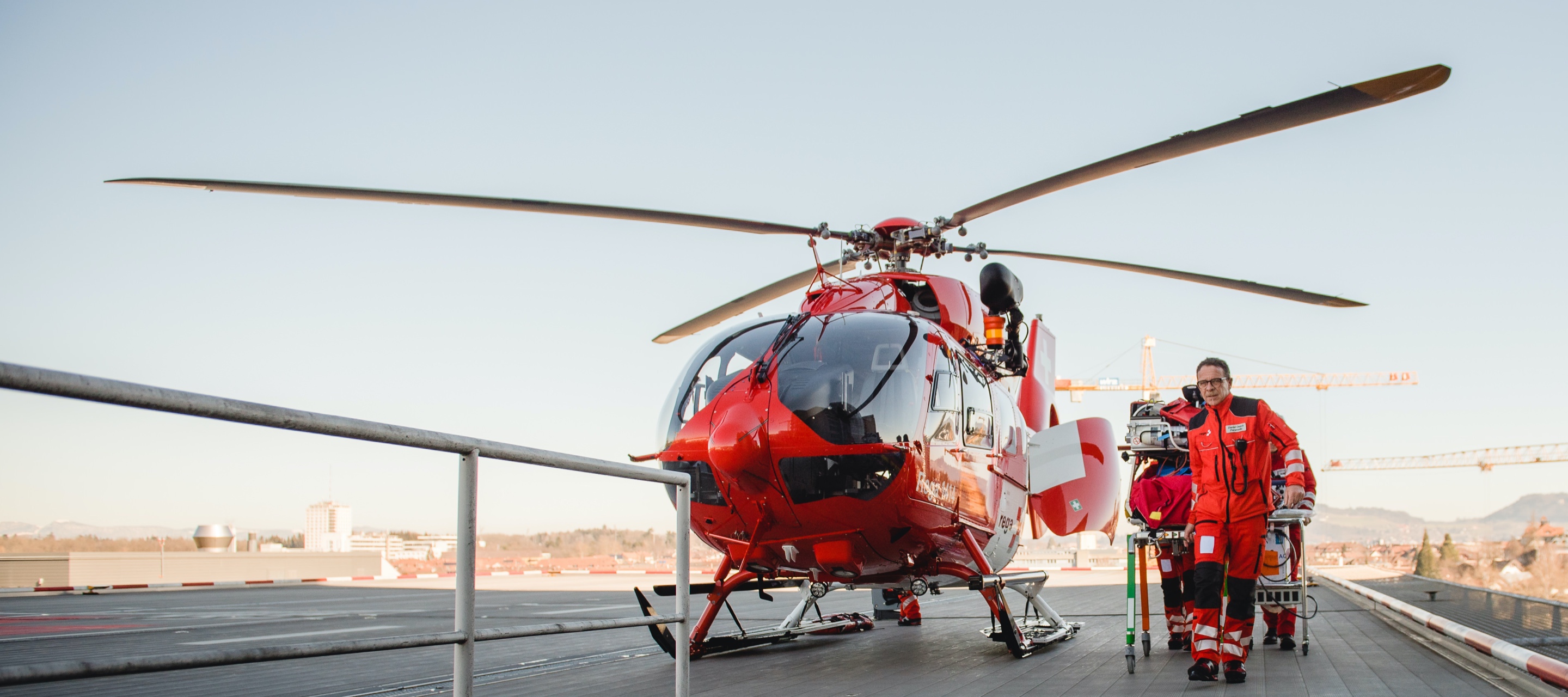 Rega helicopter next to a paramedic and a stretcher